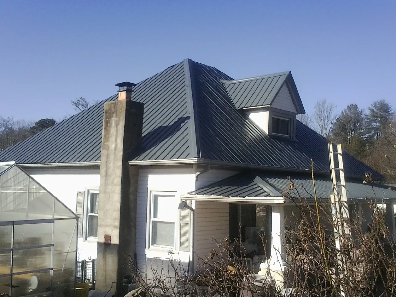 Dark blue standing seam metal roof on a white farmhouse with dormer — Slate & Tile Roof Repair by Roofing Brothers in Villa Park