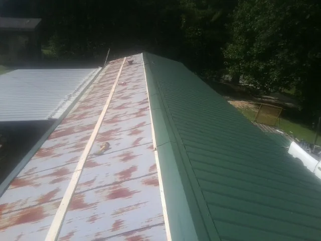 Old rusted panels beside newly installed green metal roofing — Wind Damage Roof Repair by Roofing Brothers in Villa Park