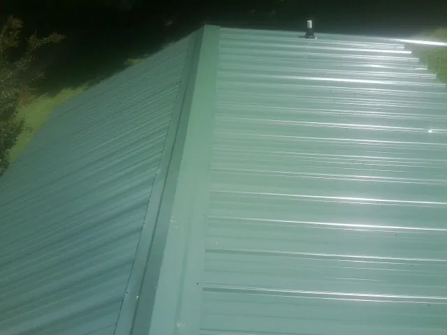 New green metal panels meeting at the ridge of a roof — Flat Roof Repair work by our crew in Villa Park