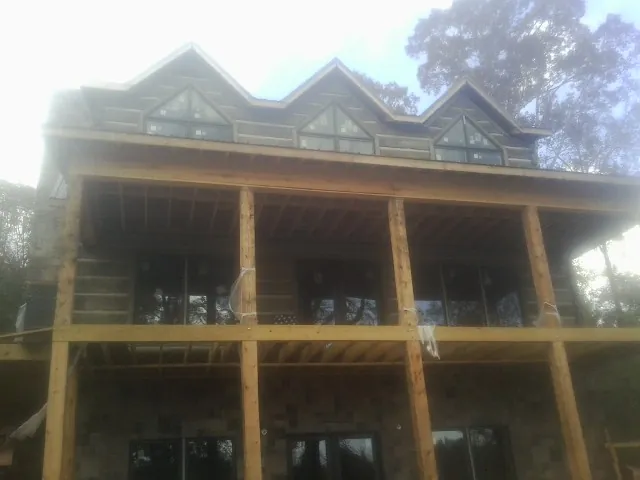 Dormers and porch framing on a large log home under construction — Roof Coating work by our crew in Villa Park
