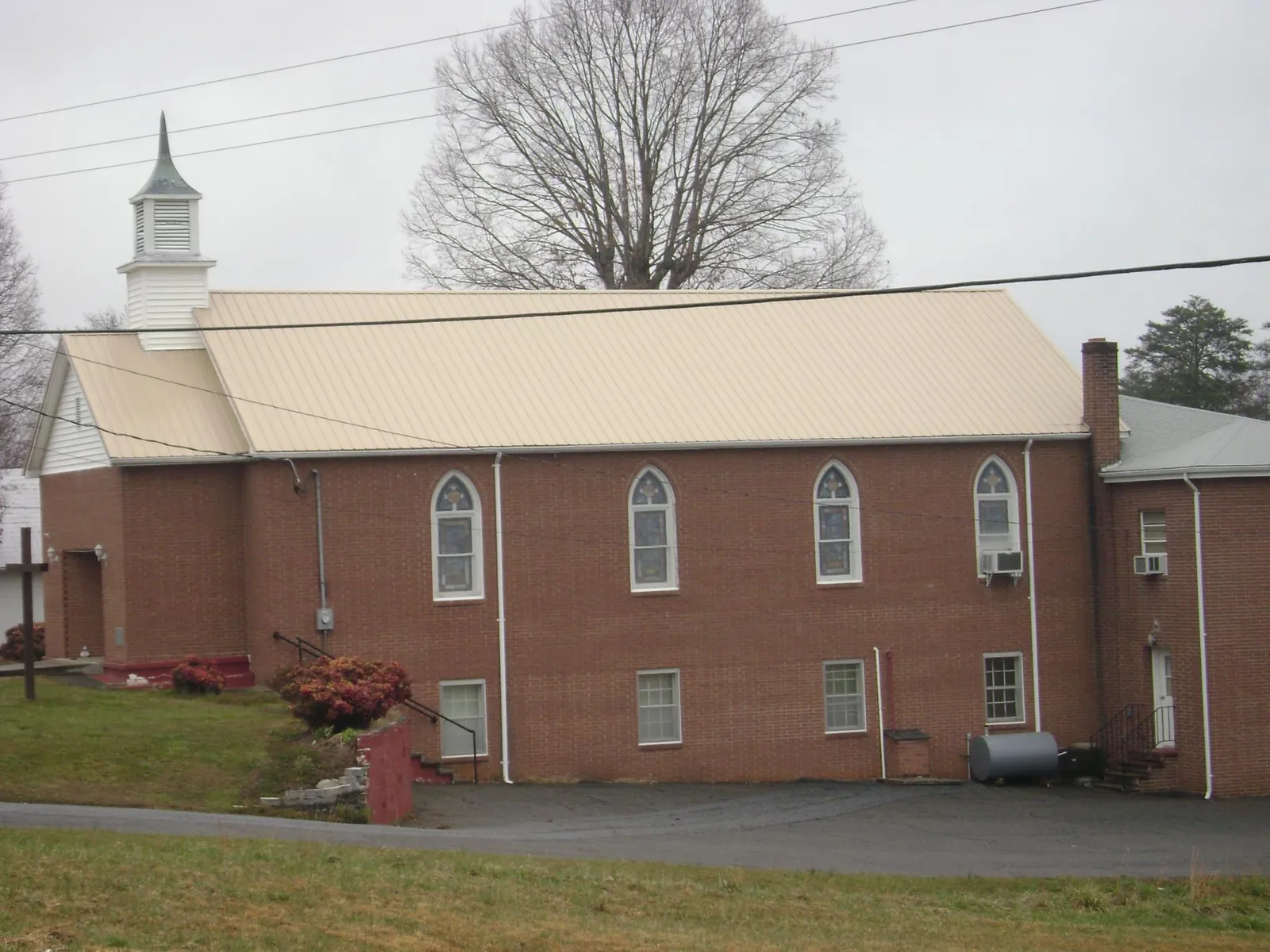 New tan metal roof on a brick church with a white steeple in Villa Park