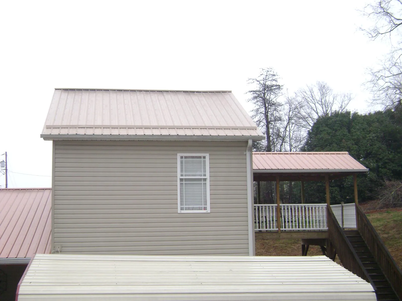 Tan metal roofs on a two story addition and attached porch, from a Roof Replacement job in Villa Park