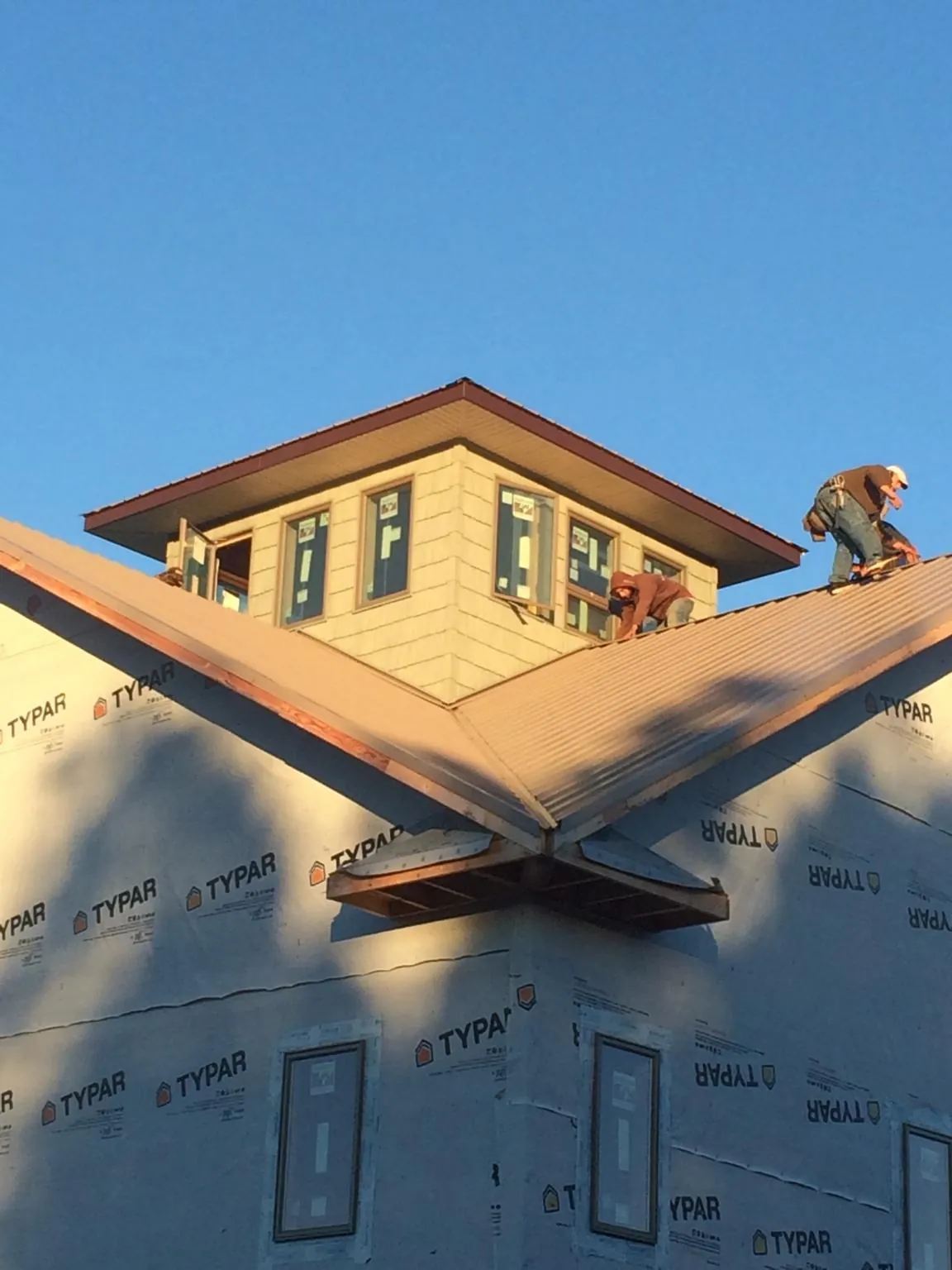 Roofers working around a rooftop cupola on a new metal roof at sunset — Roof Waterproofing in Villa Park by Roofing Brothers